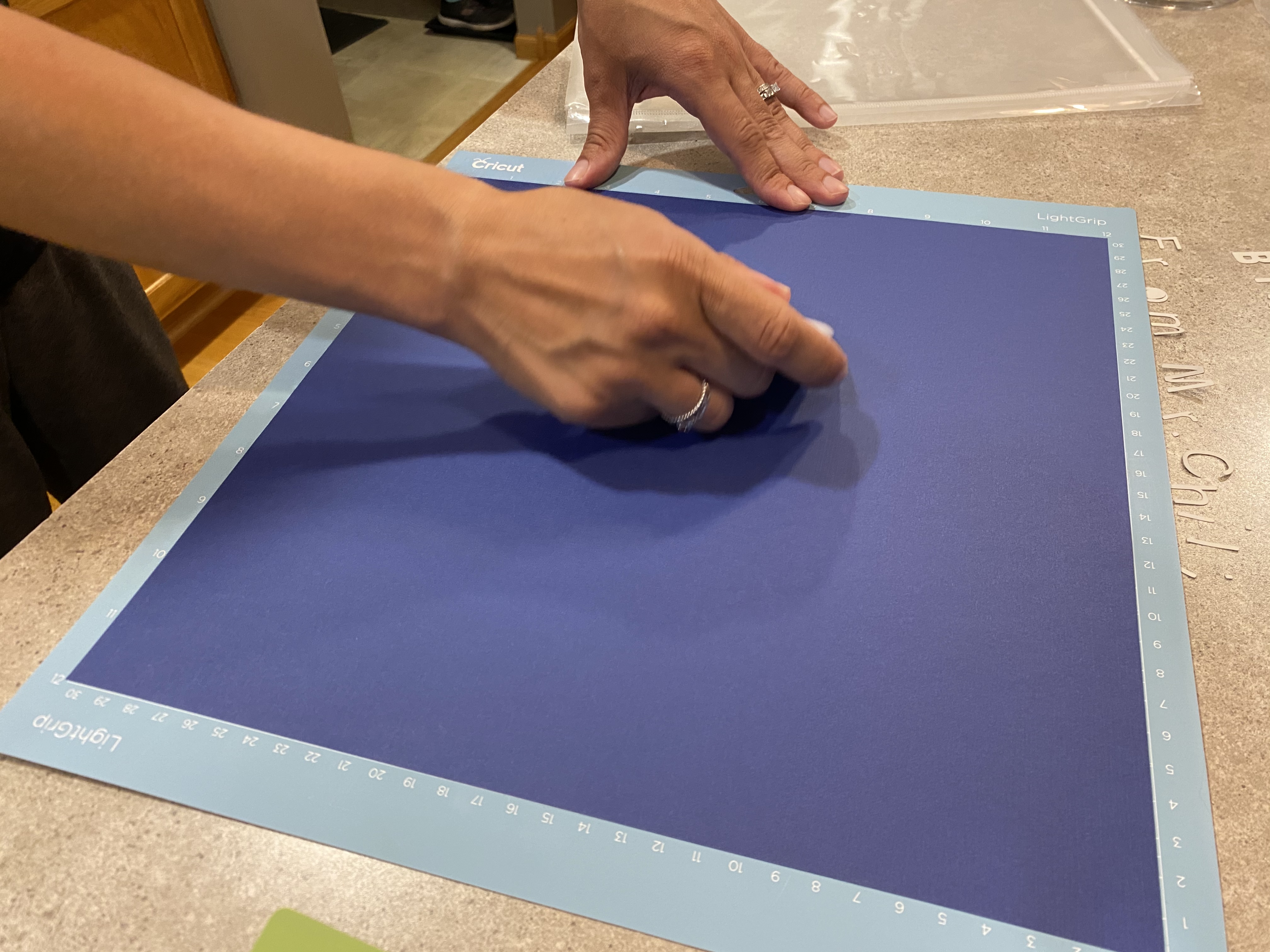 Using a scraper to adhere the cardstock to the Cricut mat