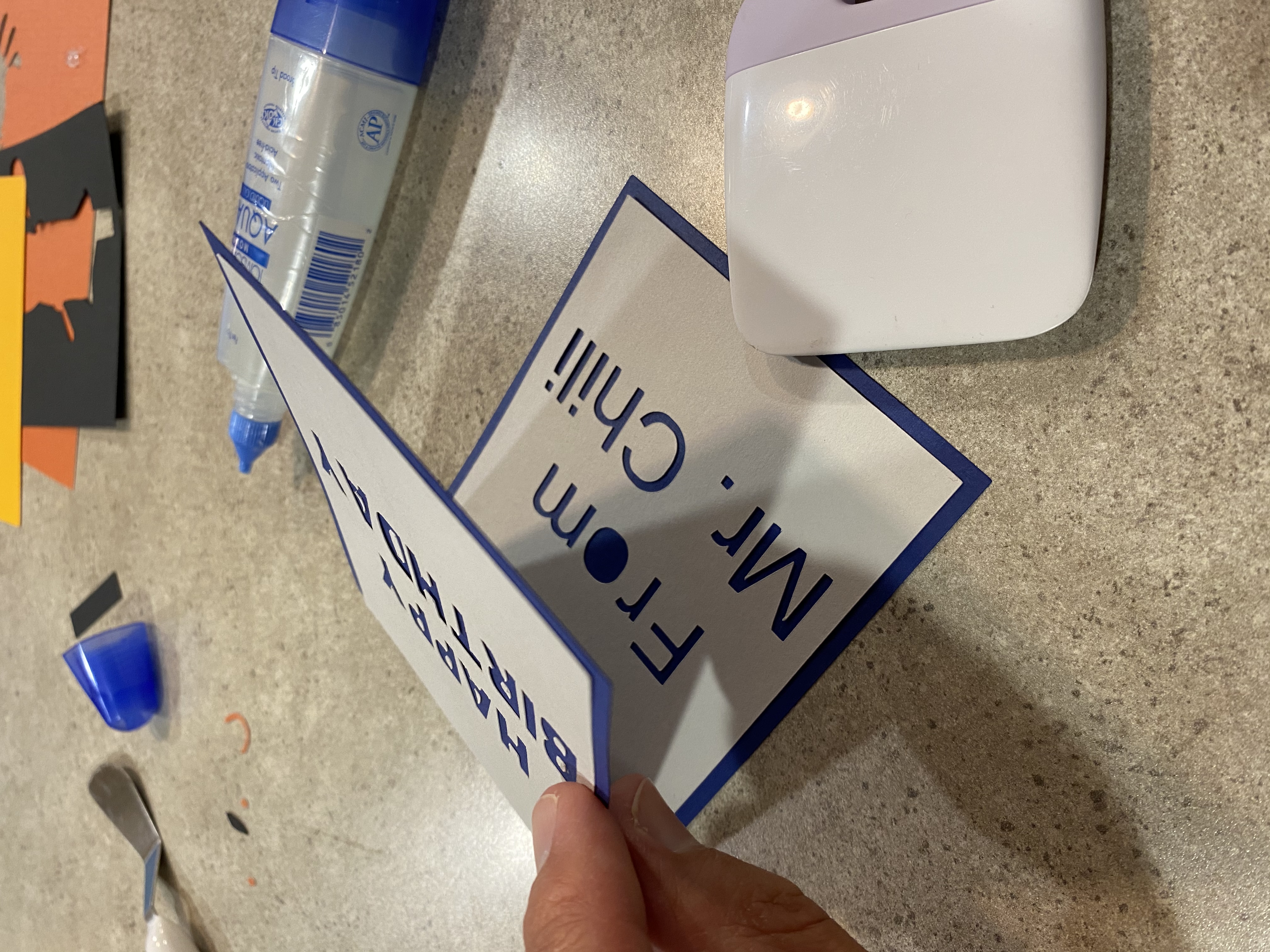 White lettering pieces have been glued to the blue card